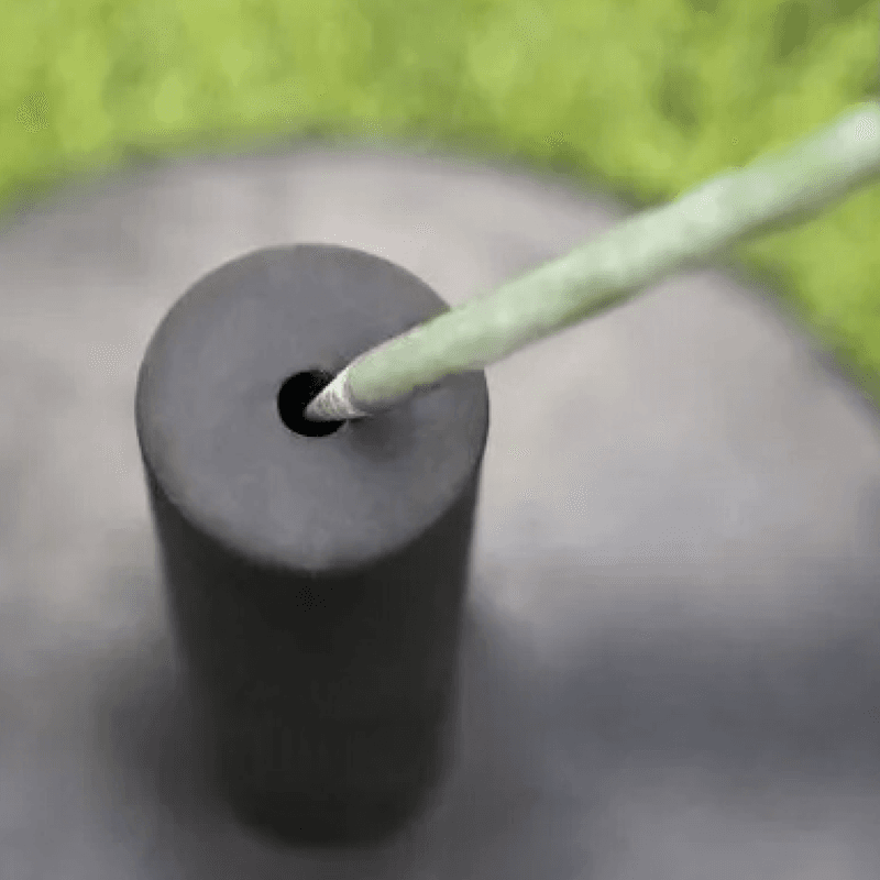 Close-up of a green agility pole inserted into a black weighted training base.