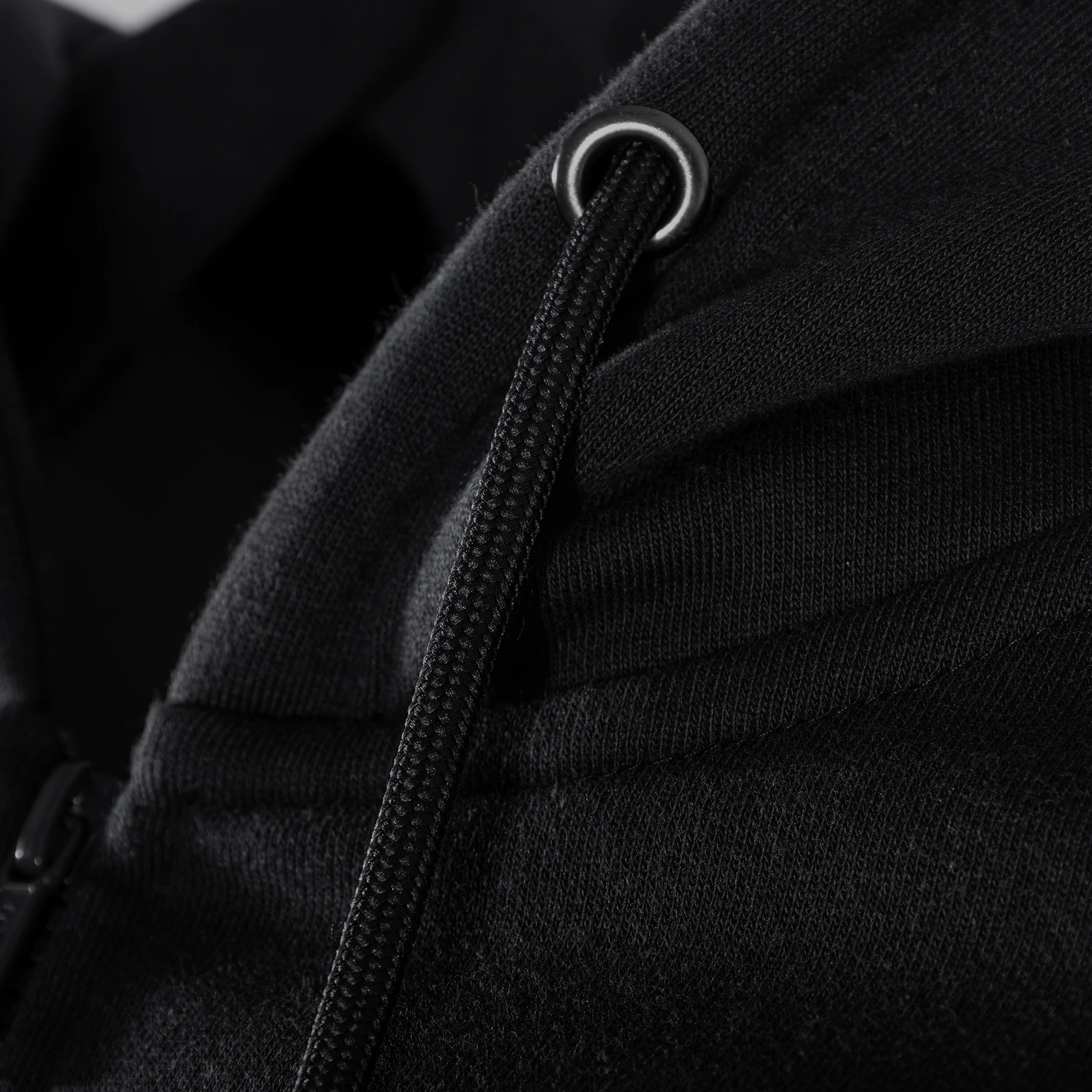 Close-up of black hoodie fabric and drawstring detail.