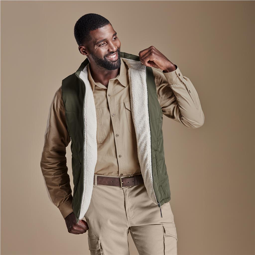 Male model wearing an olive green bodywarmer over a beige shirt.