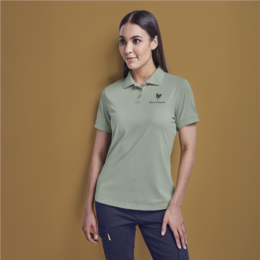 Female model wearing a sage green branded golf shirt.